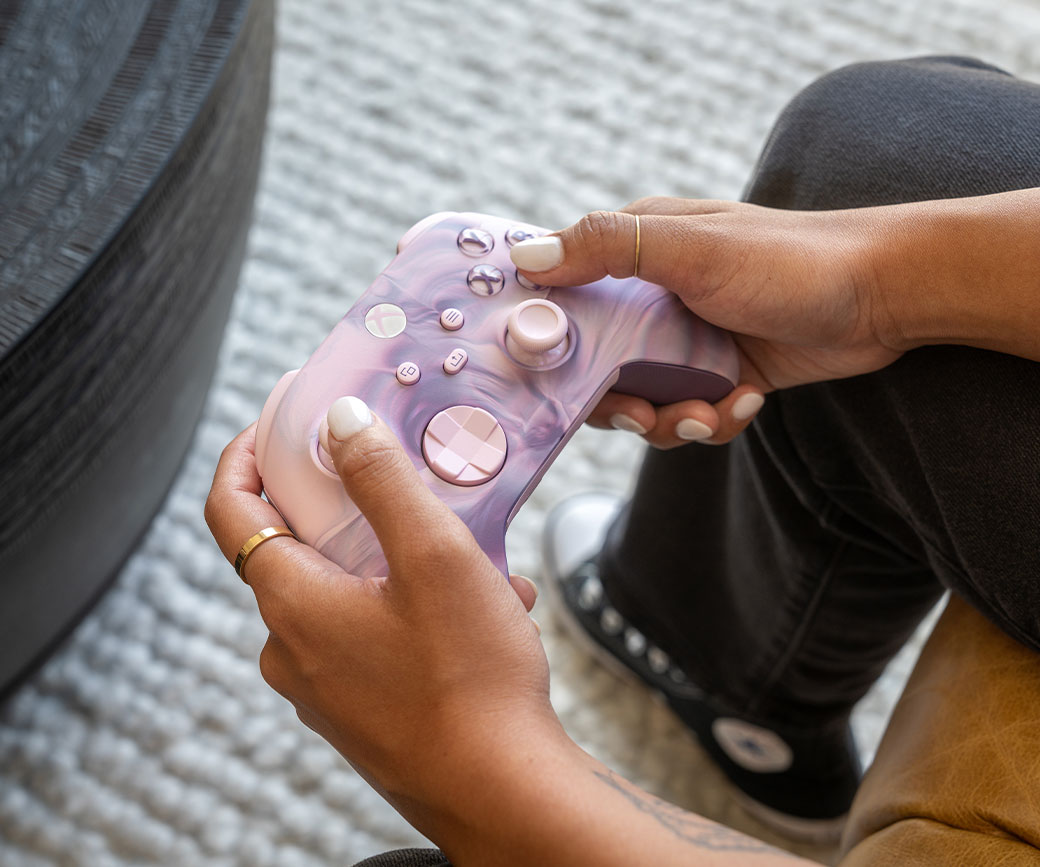 A player in their living room holds an Xbox Wireless Controller – Dream Vapor Special Edition.