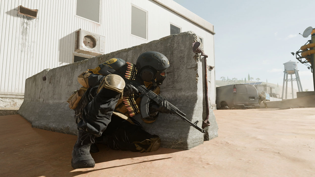 An Operator peers around a concrete barricade.