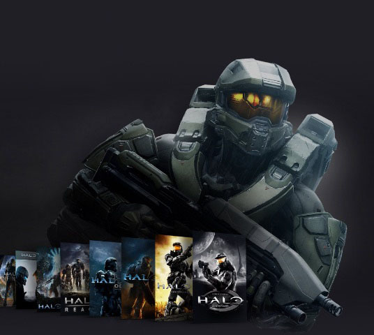 Master Chief, de pie, detrás de una colección de imágenes de la caja de la franquicia Halo.