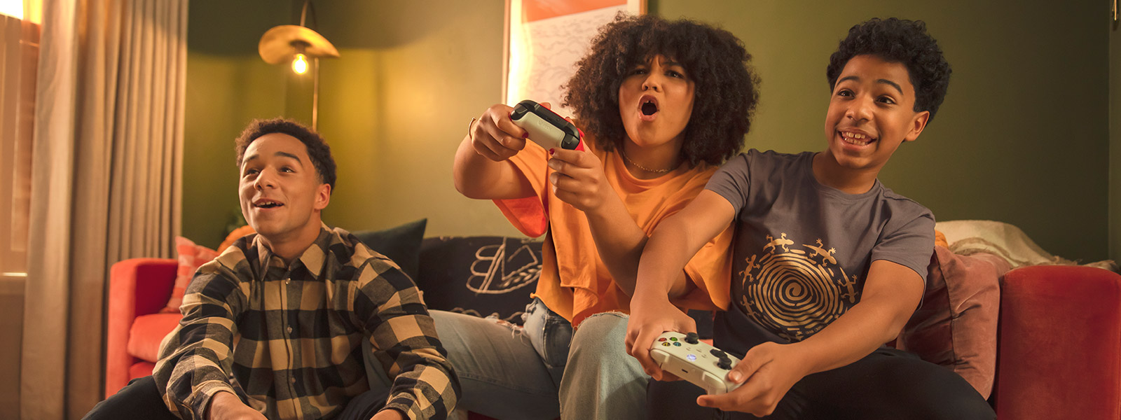 Three kids sitting on a sofa gaming on an Xbox system.