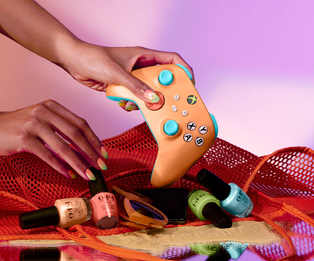 Hand reaches into a beach bag to hold Xbox Wireless Controller – Sunkissed Vibes OPI Special Edition among sunglasses and nail polish.