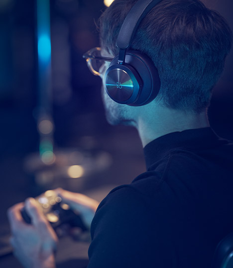 Eine Person, die den Bang & Olufsen-Kopfhörer im Sitzen trägt und auf der Xbox Series X spielt