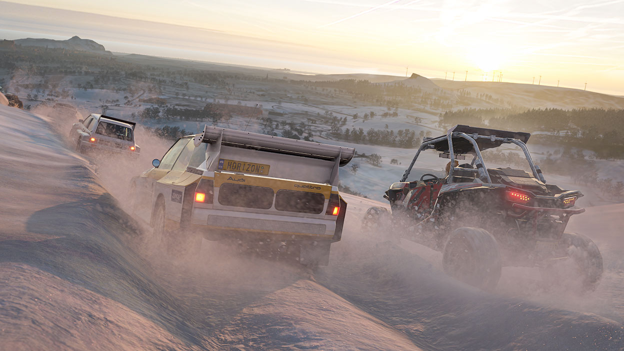 Two Audis and utility vehicle race through the snow on steep slope