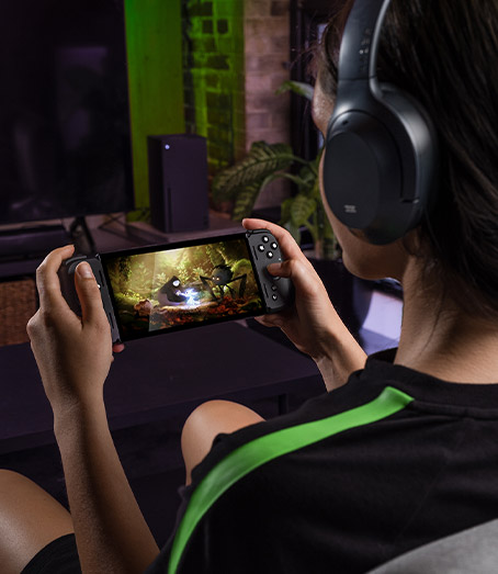Looking over the shoulder of a person with headphones holding the Razer Edge controller.