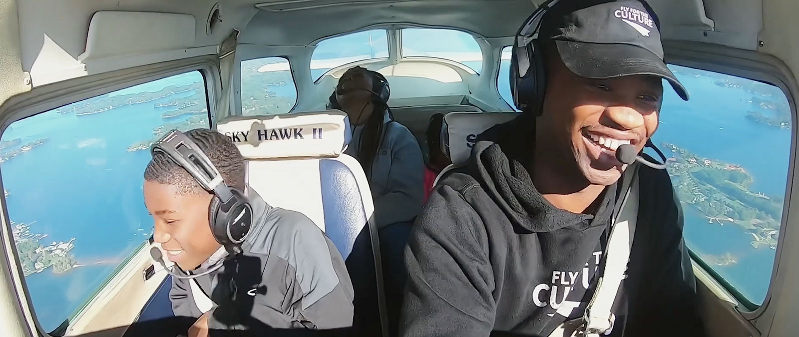 Pilot Courtland and his family smile while flying above water and land.