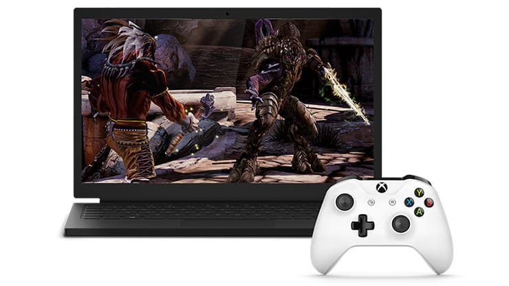 Laptop met een videogame naast een witte Xbox draadloze controller