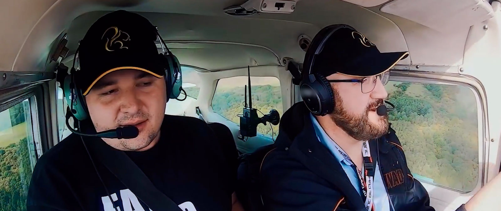 Zwei Personen mit Headsets und Hüten fliegen ein Flugzeug
