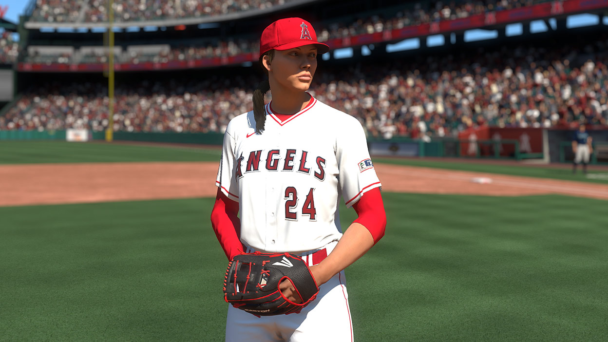 A woman in a number 24 Los Angeles Angels uniform stands on a pitcher’s mound with a ball in her mitt.