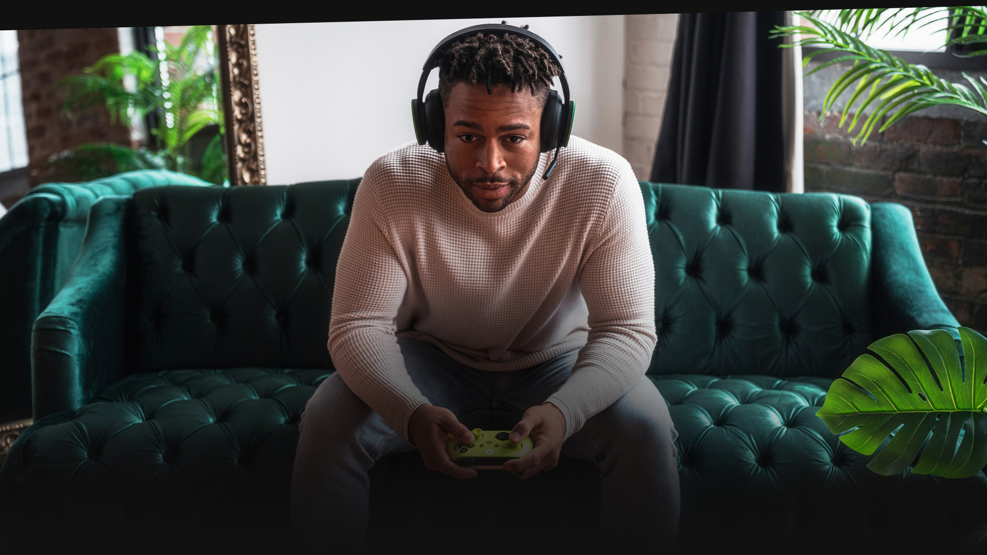 Člověk s náhlavní soupravou hraje na gauči na Xboxu