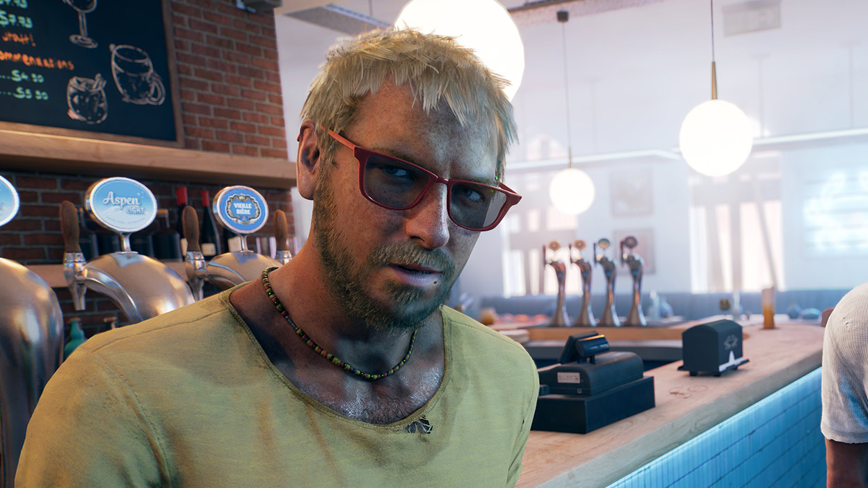 A man in a yellow shirt and sunglasses leans against a bar table.