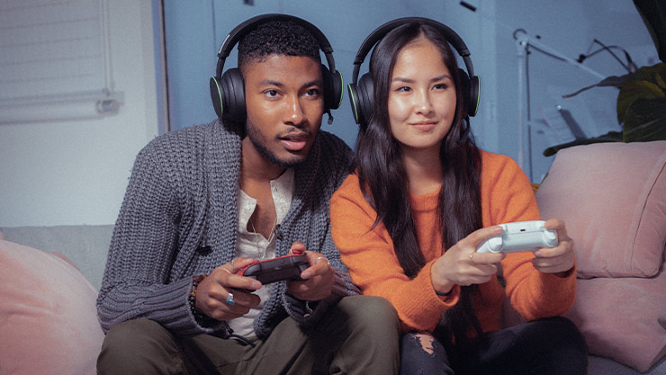 Xbox oyun kumandaları tutan ve birlikte çok oyunculu oyunlar oynayan iki kişi.