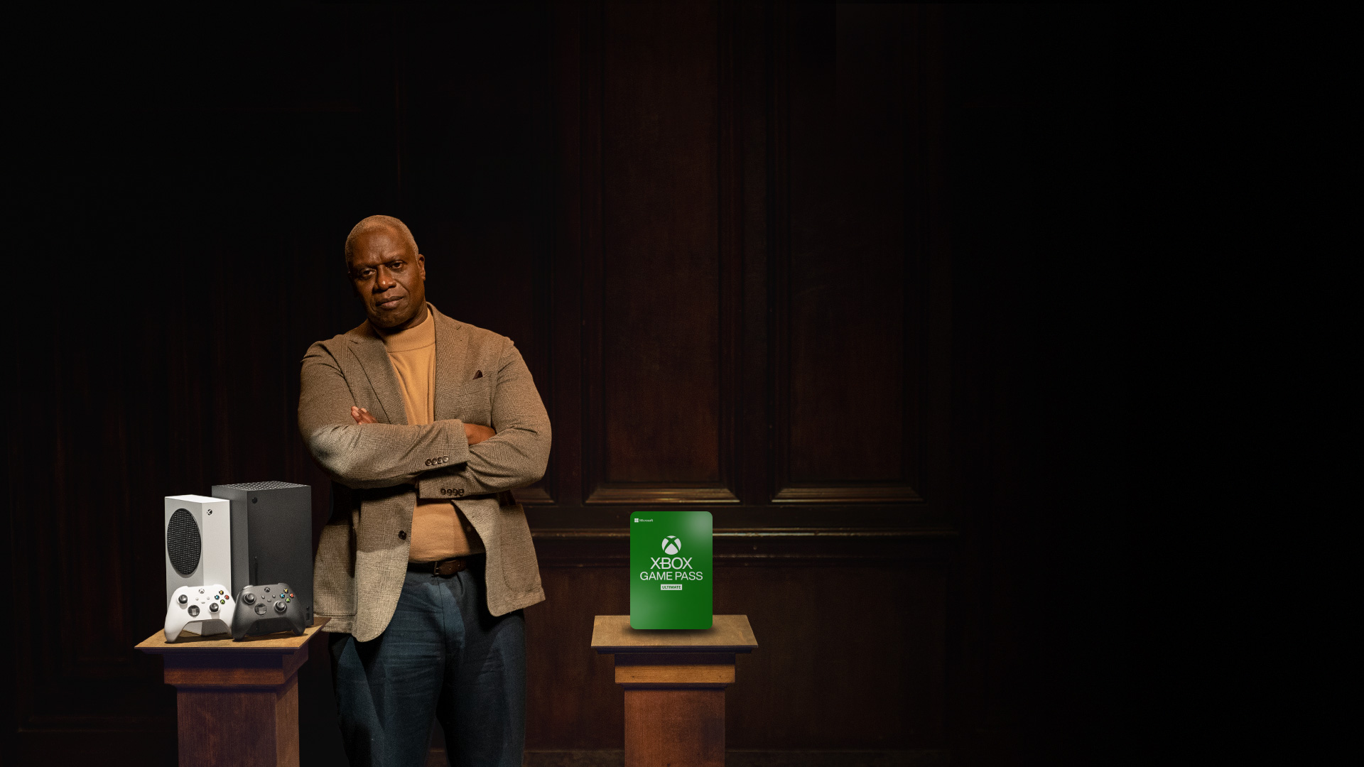 Xbox All Access. Andre Braugher stands with his arms crossed behind two pillars that are holding Xbox Series X and Xbox Series S consoles, and 24 months of Xbox Game Pass Ultimate.