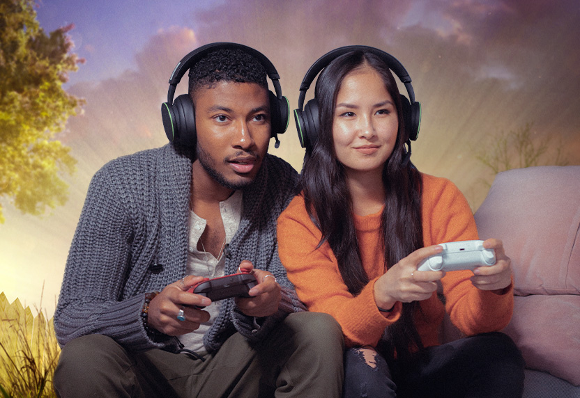 Two people wearing headsets playing Xbox games on a sofa together