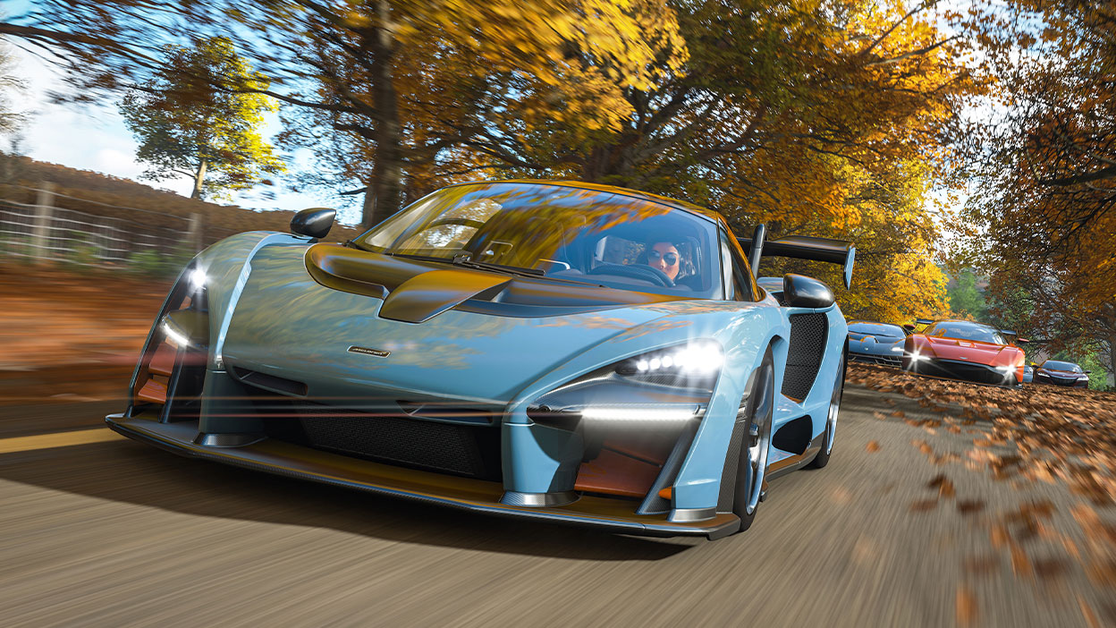 Ein McLaren Senna rast eine von Bäumen gesäumte Allee hinunter