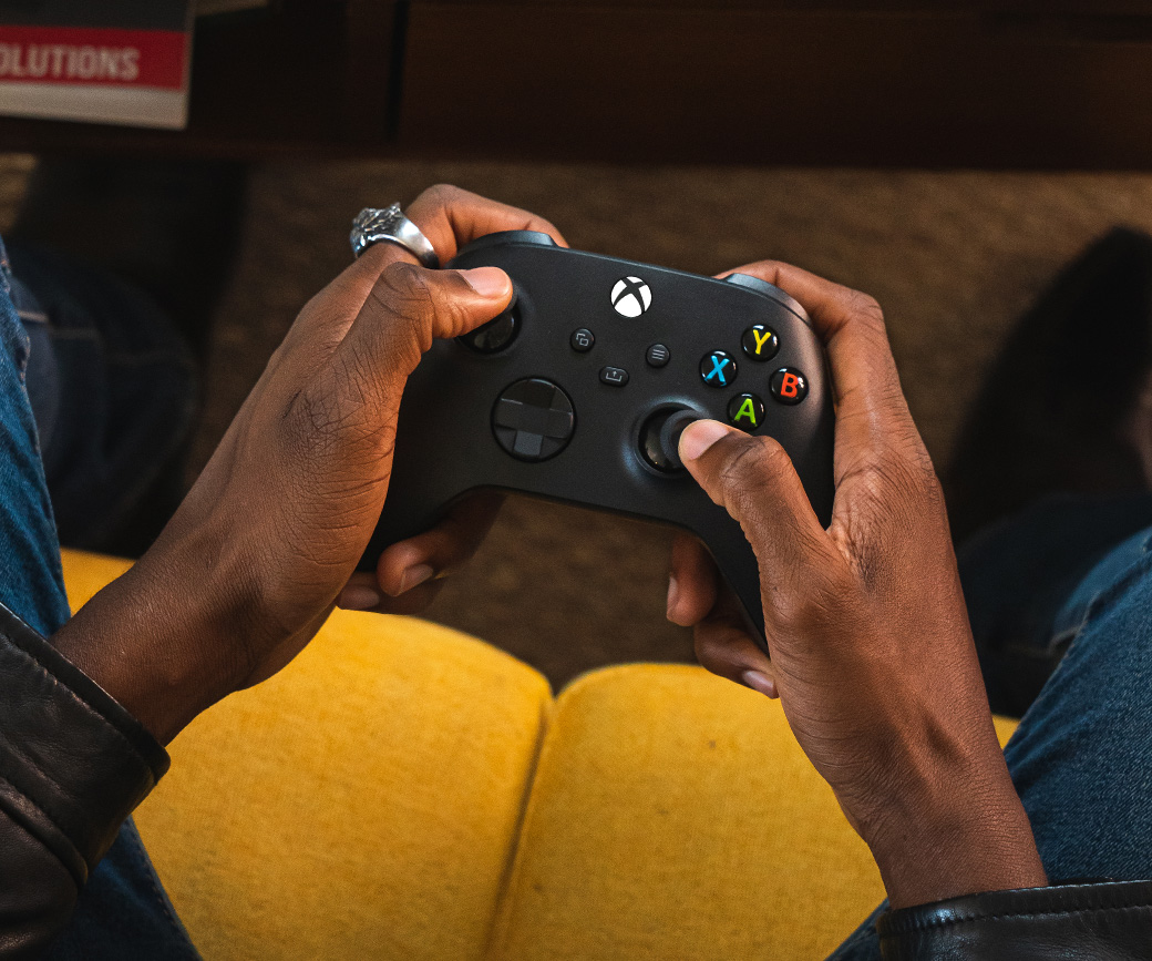 Top view of someone holding the Xbox Wireless Controller on the sofa