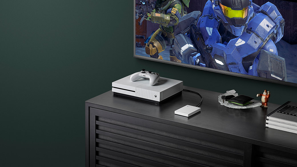 Xbox One S konzol és Xbox kontroller, felettük egy Halo 5 Guardians játékot megjelenítő TV
