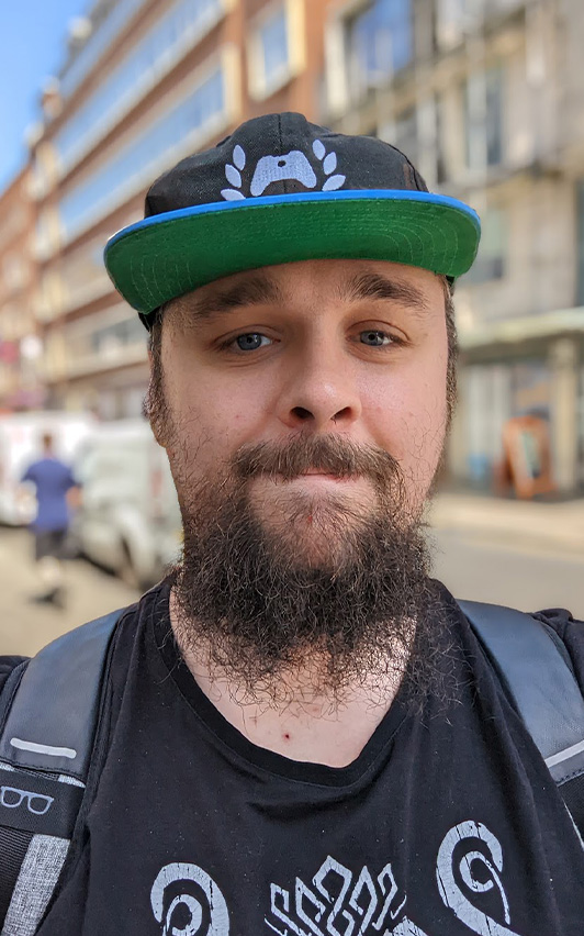 ZENOSOS standing on a sidewalk with a beard and an Xbox hat