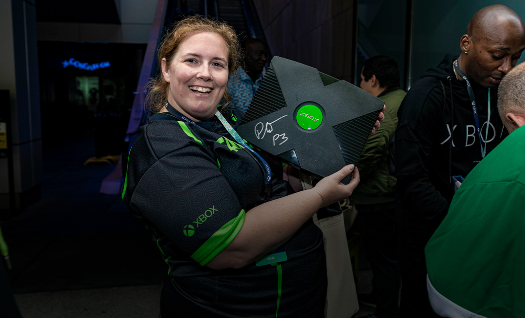 Mulher segurando e exibindo um Xbox 360 autografado.