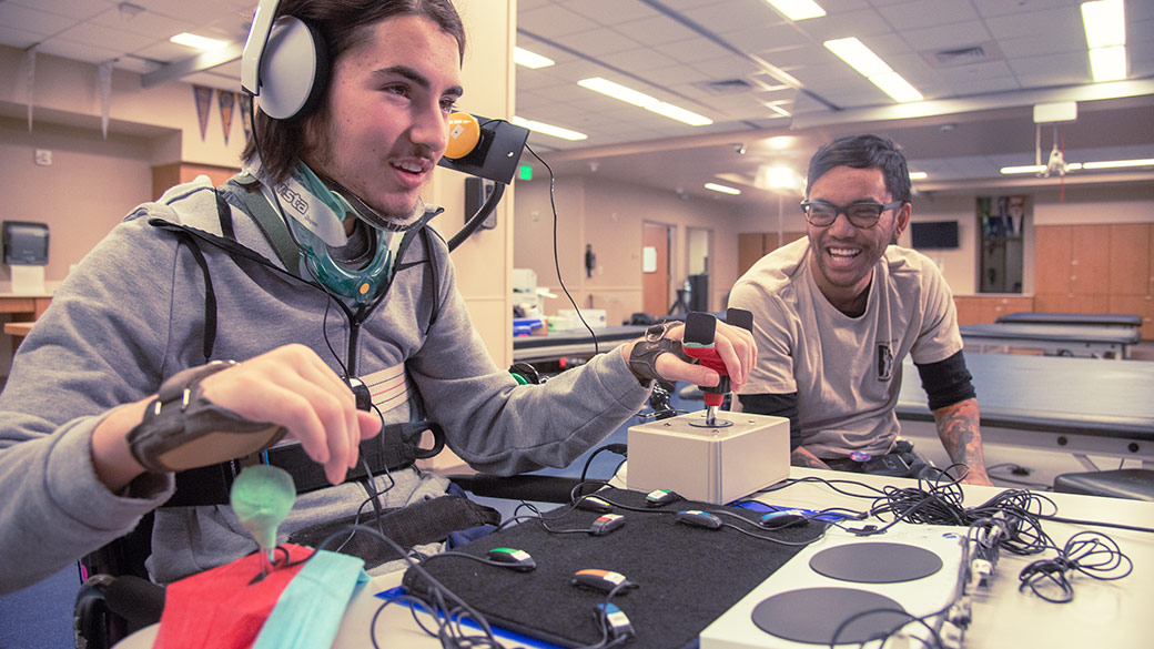 En man som använder styrspakar anslutna till en Xbox Adaptive Controller