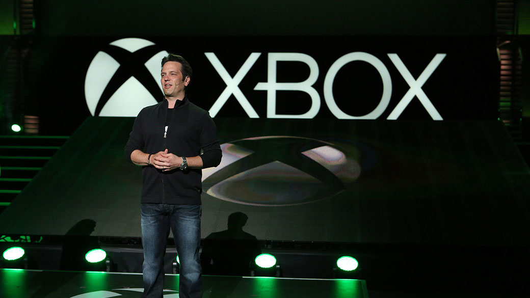 Xbox Yöneticisi Phil Spencer, bir sahnede Xbox logosunun önünde duruyor