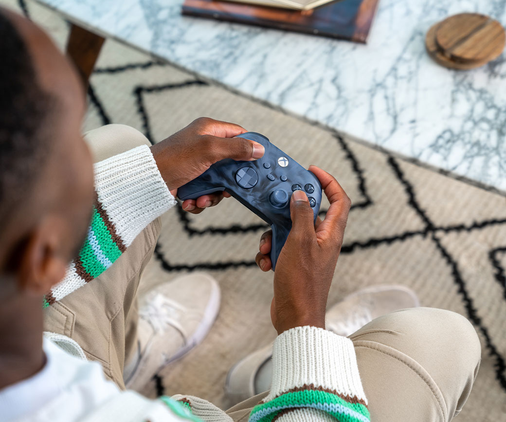 Un jugador en su sala de estar sostiene un Mando inalámbrico Xbox: Stormcloud Vapor Special Edition.