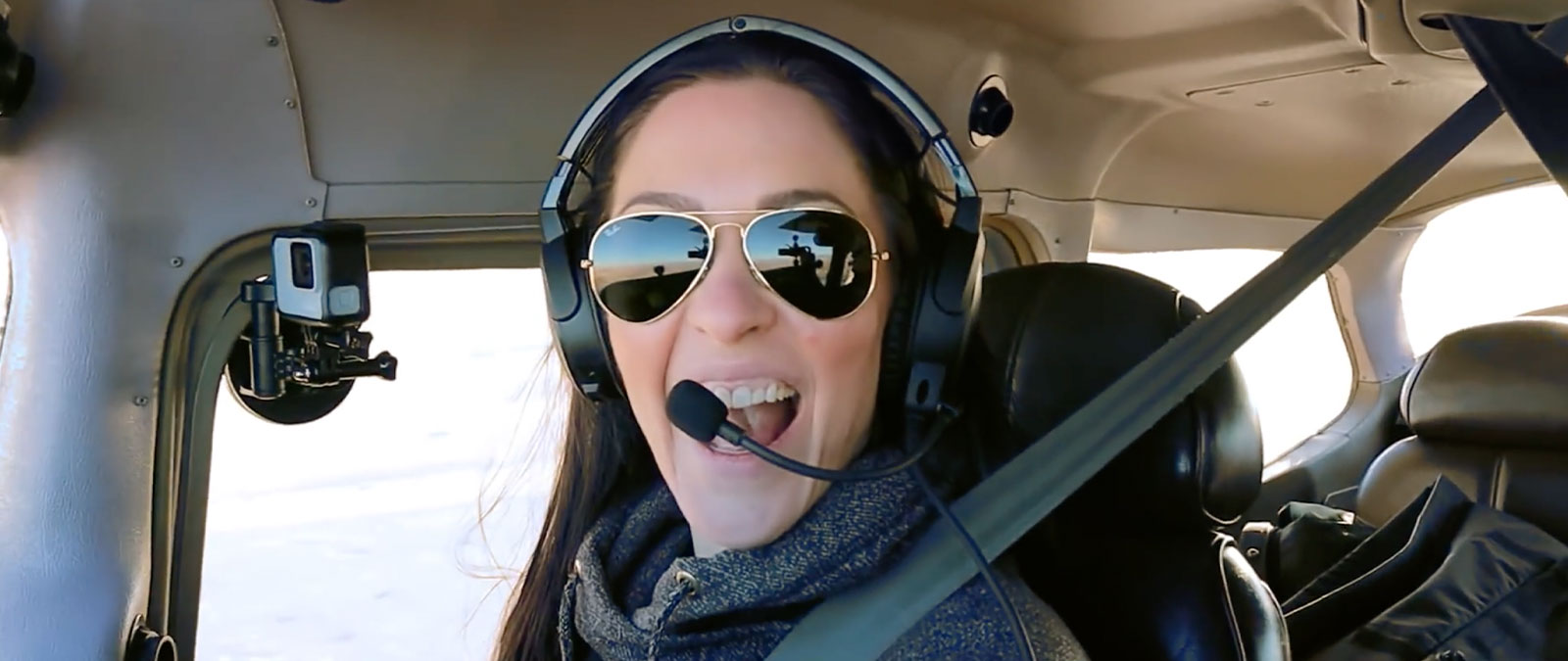 Pilot Emilie flying a plane with a headset and sunglasses