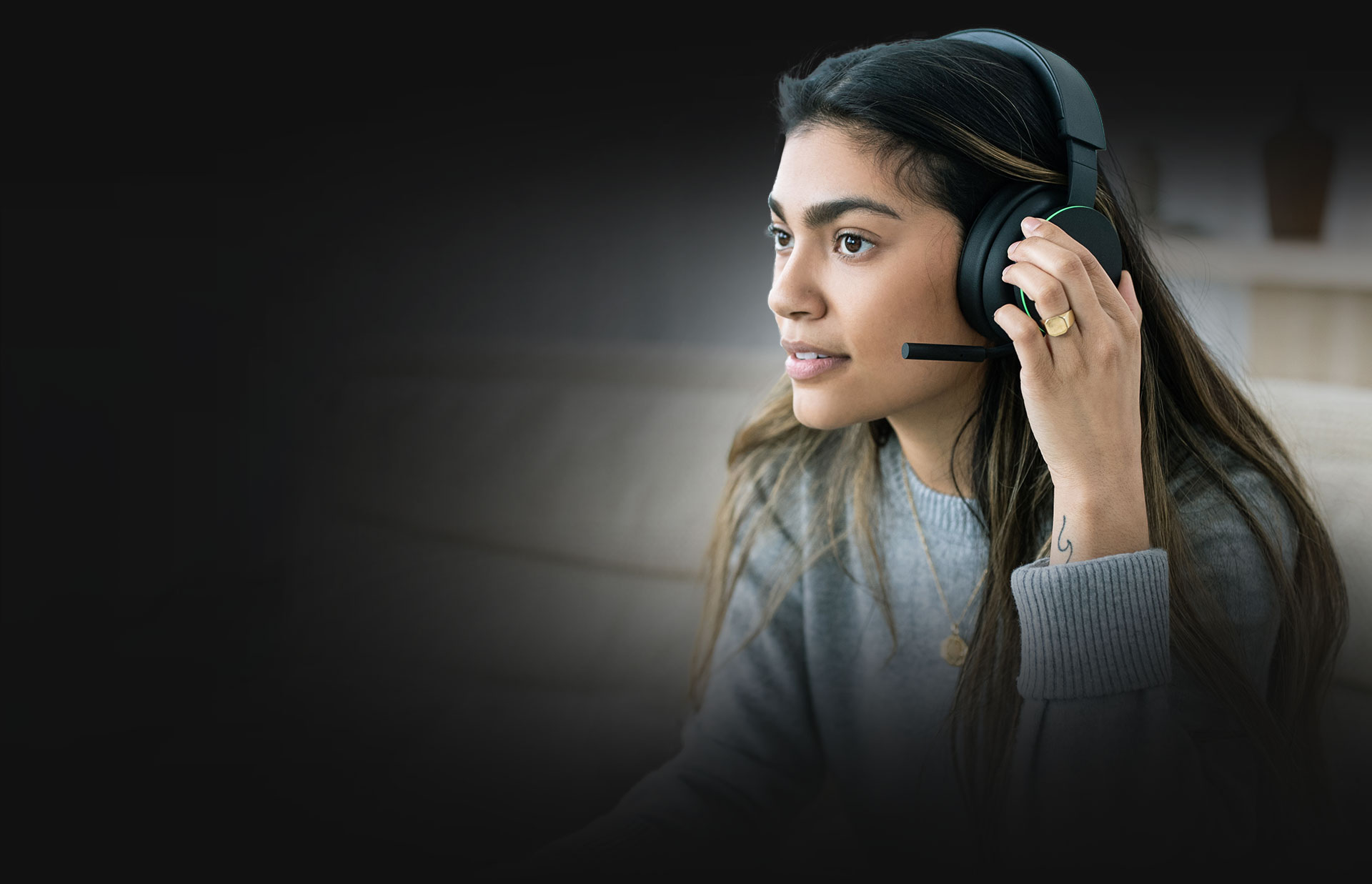 A fülpárnán található tárcsák használatával egy nő a hangerőt állítja a vezeték nélküli Xbox-headseten.