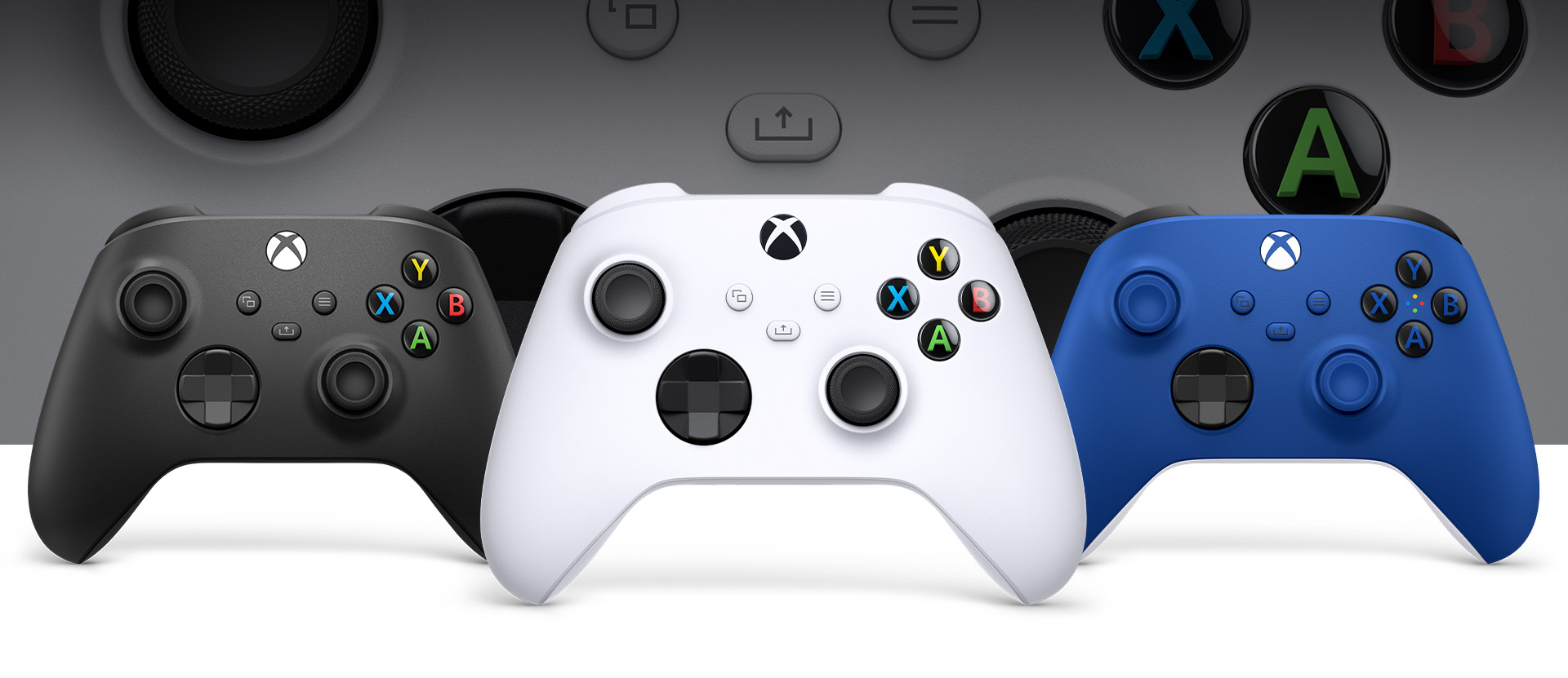 Soldaki Carbon Black ve sağdaki Shock Blue oyun kumandalarının önünde ortada duran Xbox Robot White oyun kumandası
