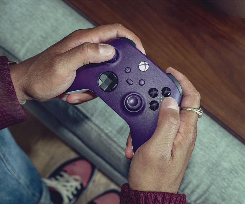 Vue du dessus d’une personne tenant la manette sans fil Xbox sur un canapé