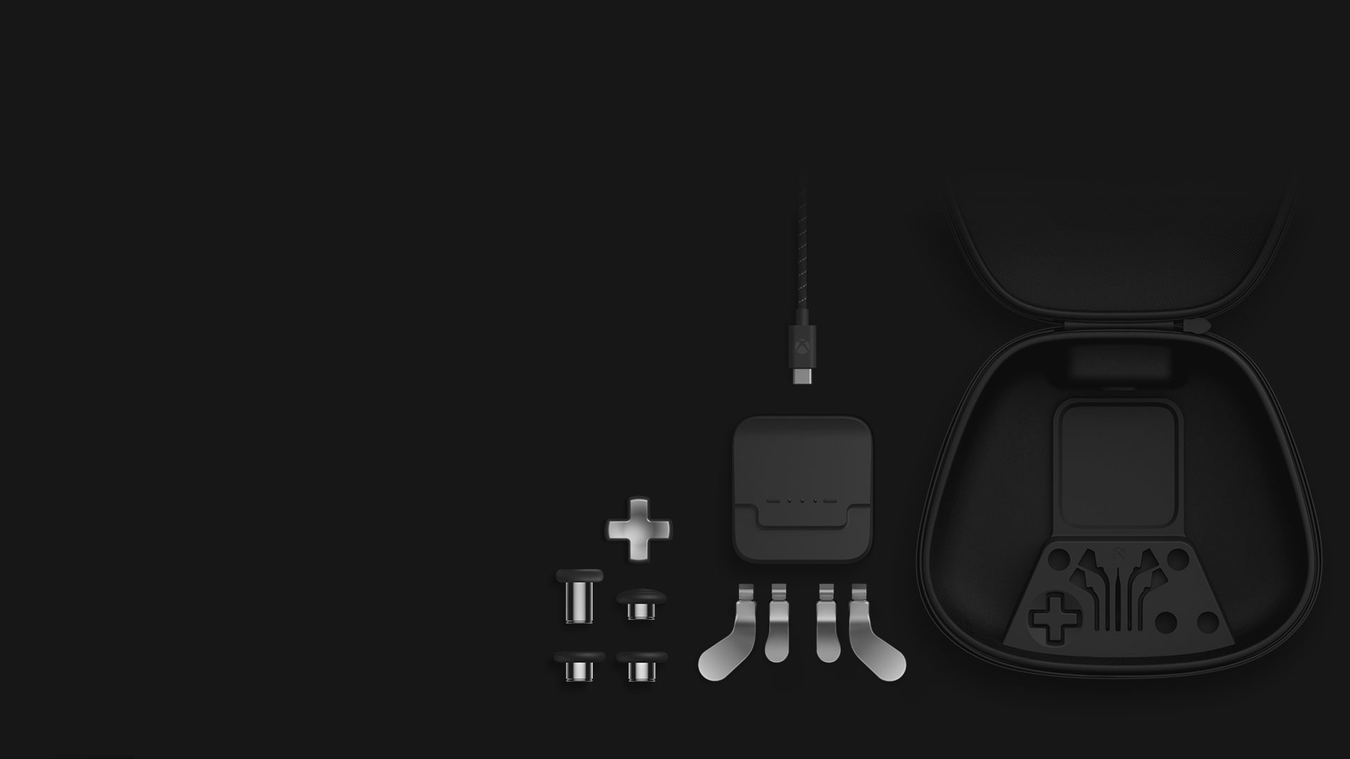 Izometrické zobrazenie obsahu kompletného balíka komponentov: pákové palcové ovládače, smerový ovládač, lopatkové pákové ovládače, dobíjací stojan, USB-C kábel a prenosné puzdro.