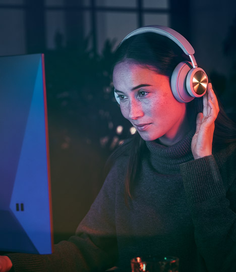 A woman wearing the Bang and Olufsen headset while using the computer