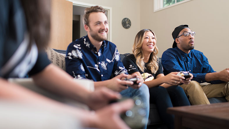 A group of four people on a couch playing Xbox together